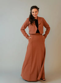 Modelo veste blazer marrom, blusa preta básica e saia longa na mesma cor do blazer.