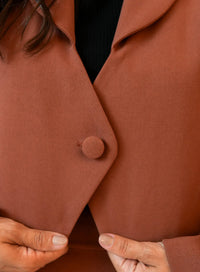 Detalhe do botão único do blazer marrom da Elaz.