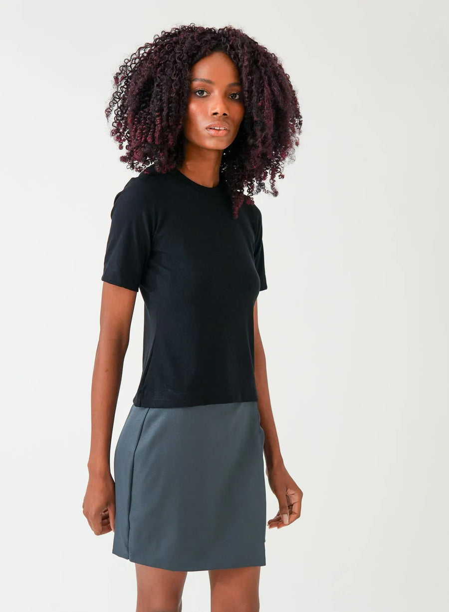 Modelo vestindo blusa tshirt na cor preta e saia na cor cinza.