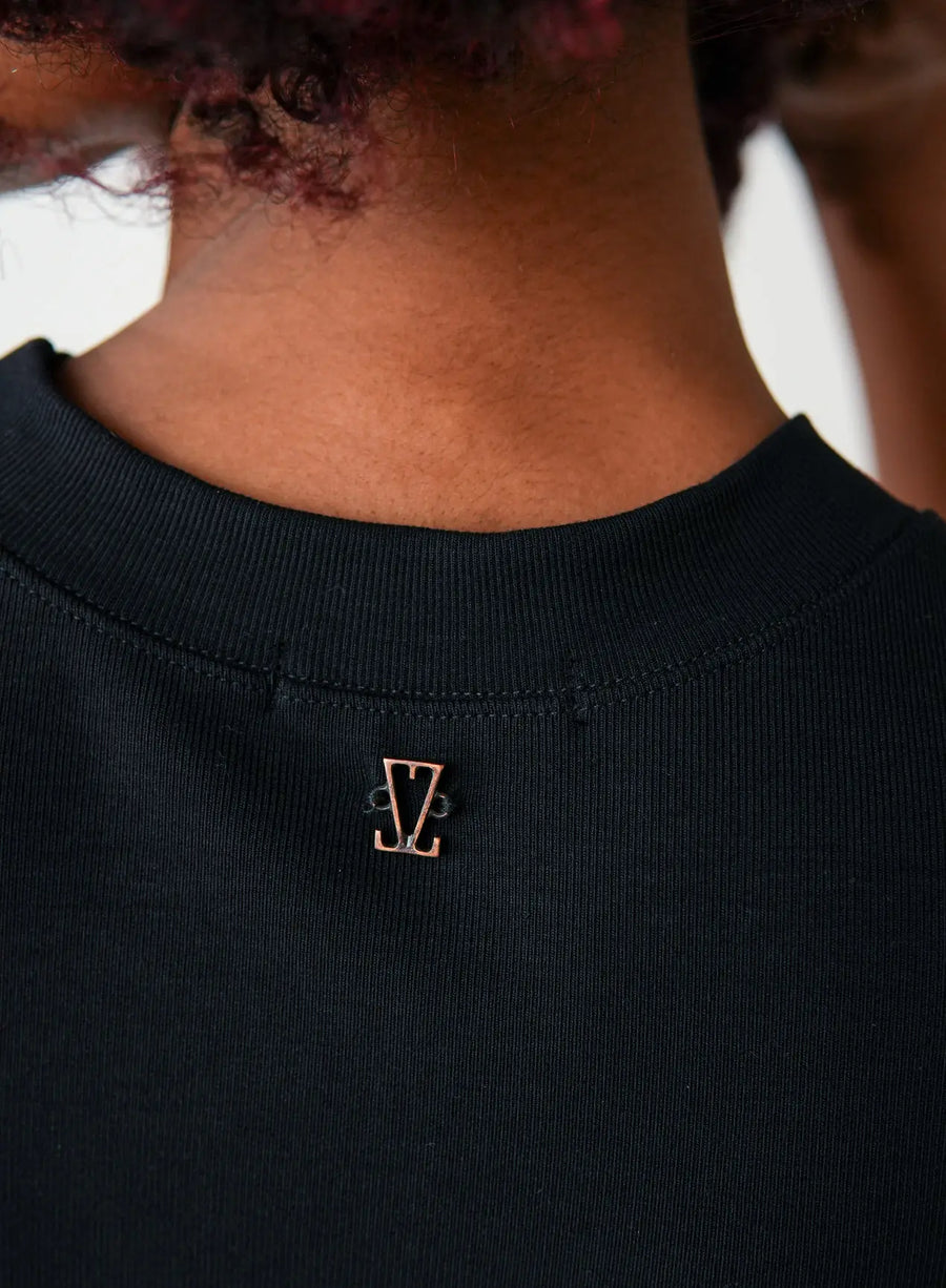 Detalhe da parte de trás da blusa tshirt preta com pequeno pingente dourado da logo da Elaz.
