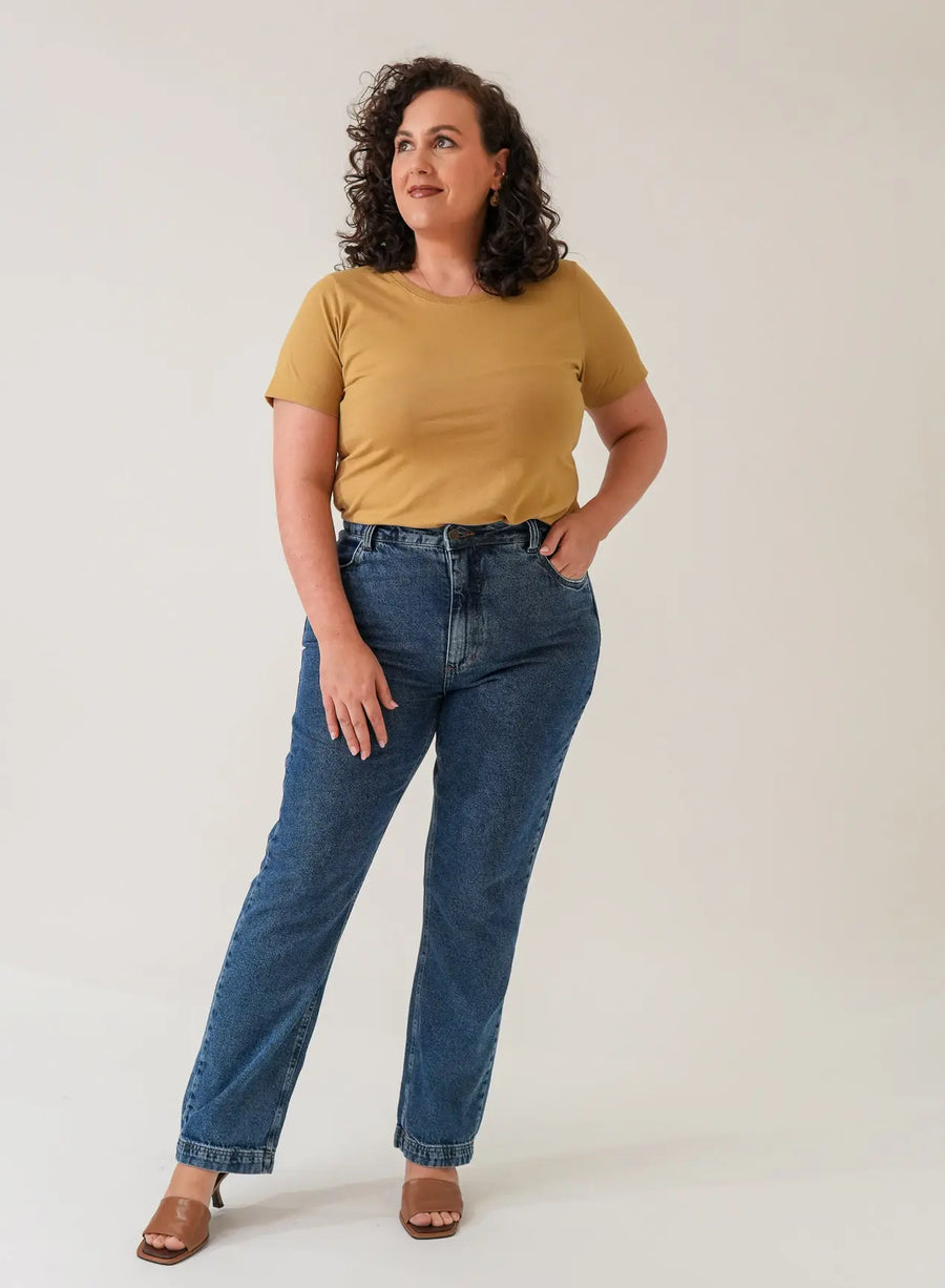 Mulher vestindo blusa tshirt, calça jeans azul e salto marrom.