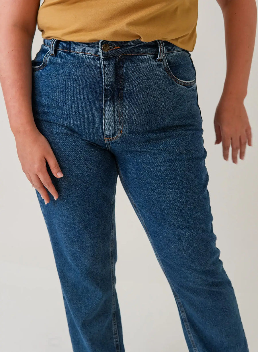 Close da calça jeans azul da Elaz, com botão, zíper e bolsos.