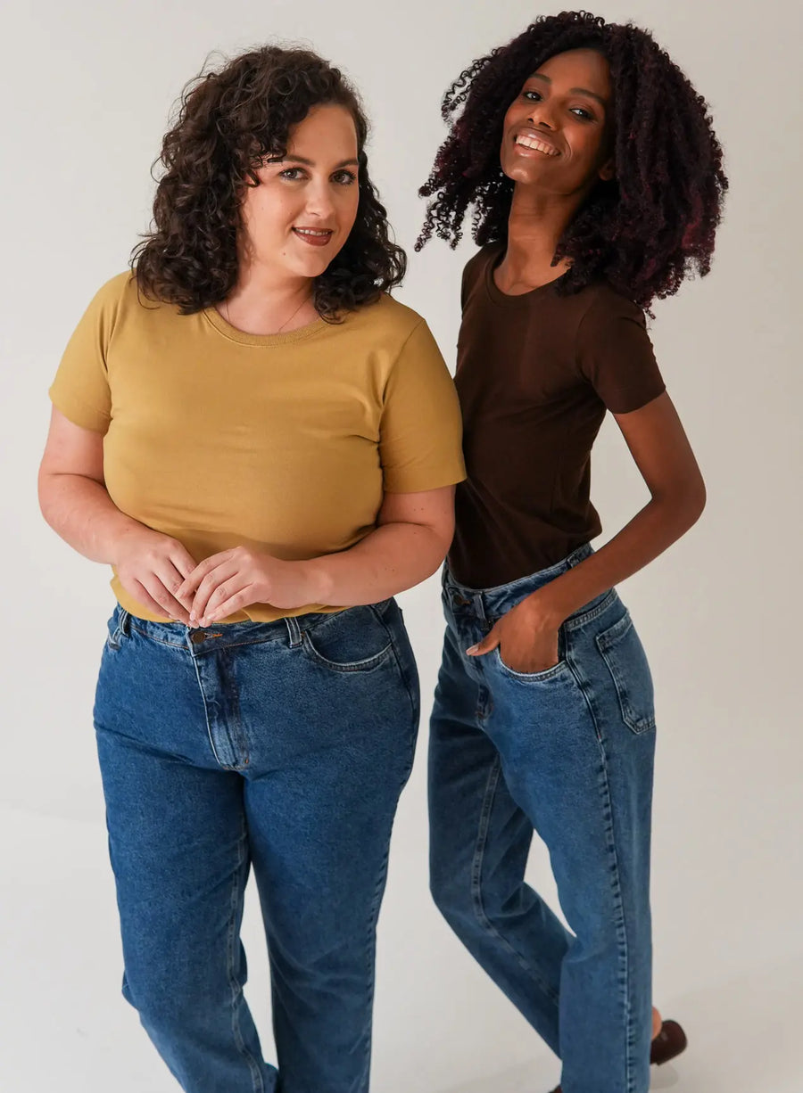 Modelos em fundo neutro exibindo calça jeans azul da Elaz.
