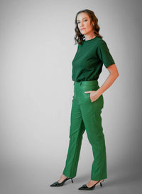 Modelo vestindo calça em viscose verde, blusa básica e scarpin preto.