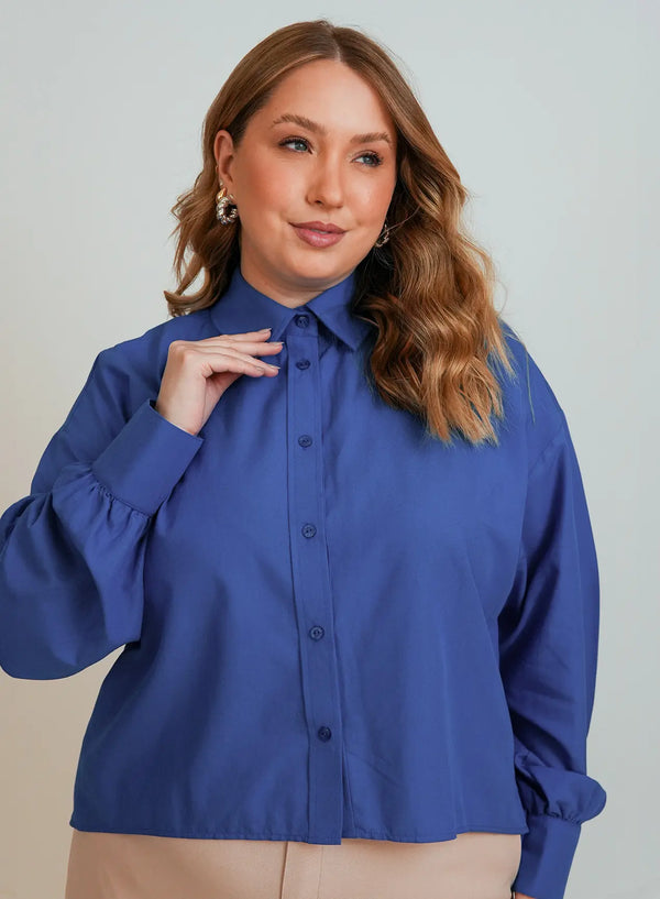 Modelo posando em fundo neutro vestindo camisa azul feminina da Elaz.