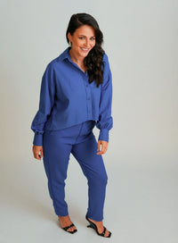 Modelo vestindo camisa azul feminina, calça da mesma cor e salto preto.