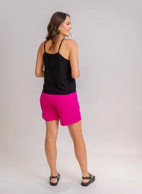Modelo de costas vestindo regata preta, shorts rosa e sandália preta.
