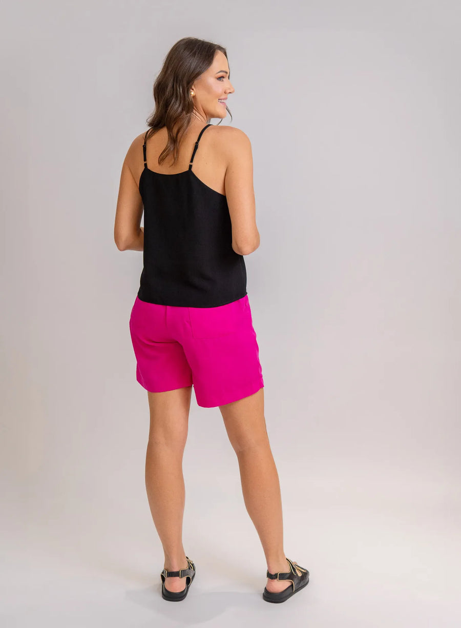 Modelo de costas vestindo regata preta, shorts rosa e sandália preta.