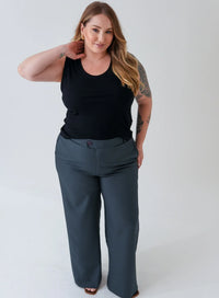 Mulher usando regata preta e calça alfaiataria. A modelo combina as peças com acessórios dourados.